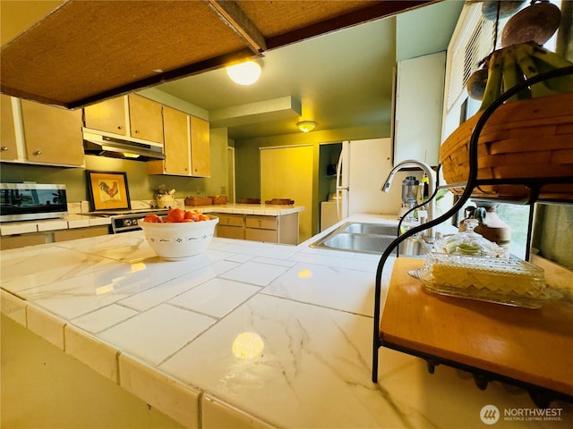 kitchen with stainless steel appliances, tile counters, a sink, a peninsula, and under cabinet range hood