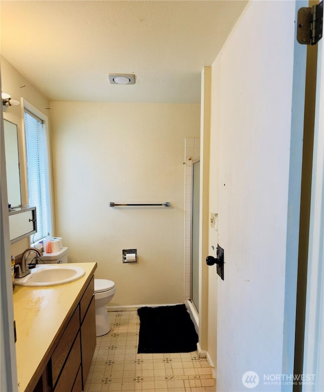 bathroom with toilet, a shower stall, vanity, baseboards, and tile patterned floors