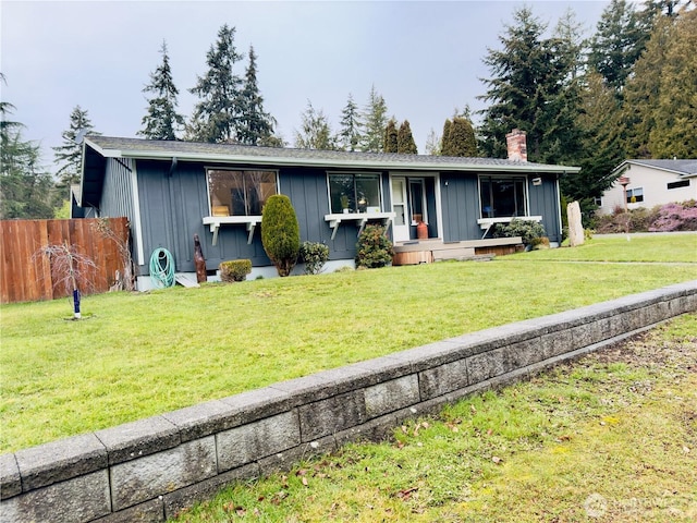 ranch-style home with a chimney, board and batten siding, a front yard, and fence