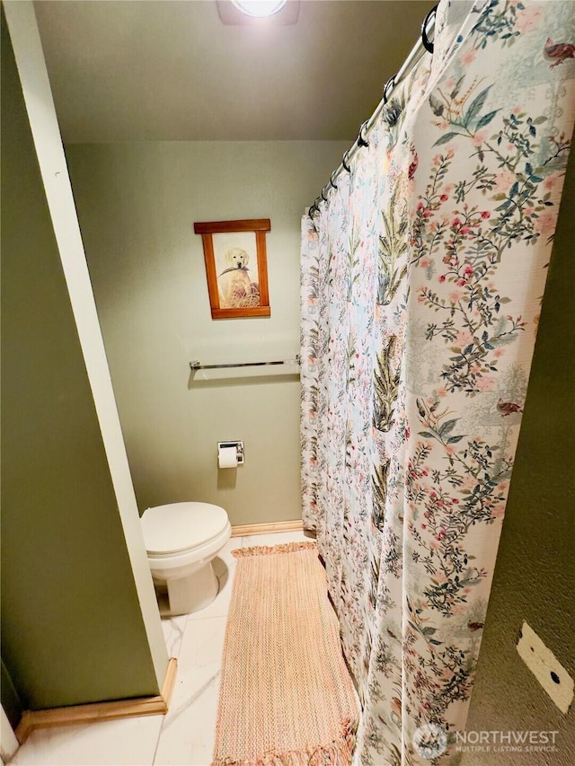 full bath with baseboards, a shower with shower curtain, and toilet