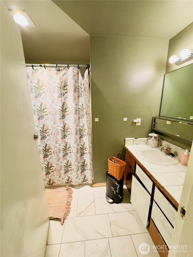 full bath featuring marble finish floor, vanity, and a shower with shower curtain