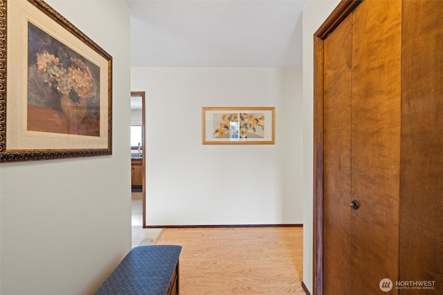 hallway with light wood-type flooring and baseboards