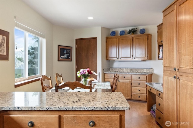 kitchen with light wood-style flooring, recessed lighting, light stone countertops, and brown cabinets