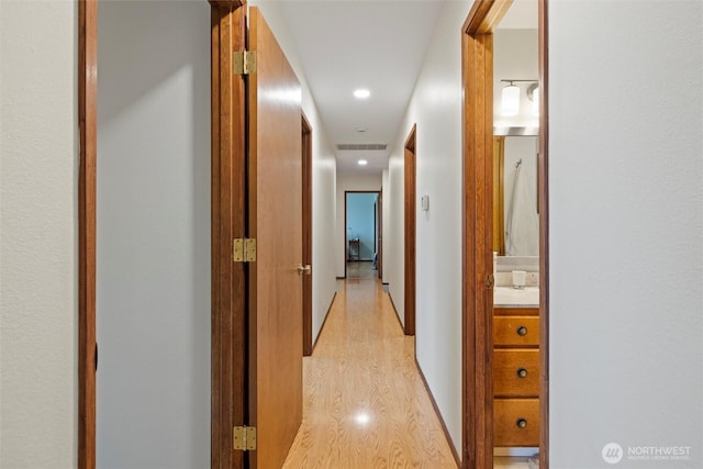 hallway featuring light wood-type flooring and recessed lighting