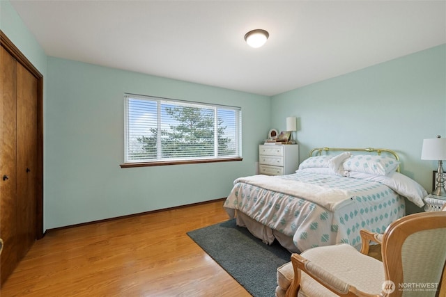 bedroom featuring light wood-style floors, baseboards, and a closet