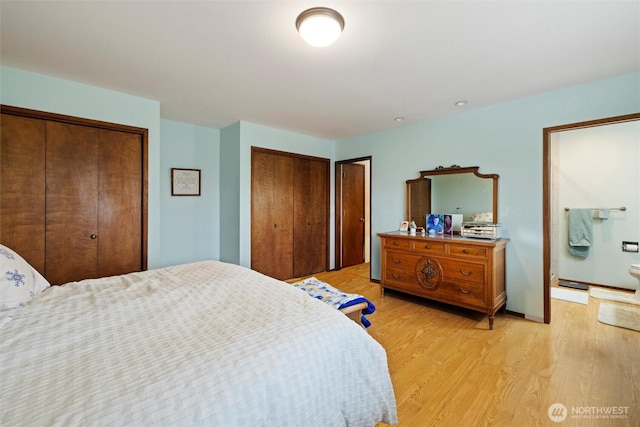 bedroom with light wood-style flooring and two closets