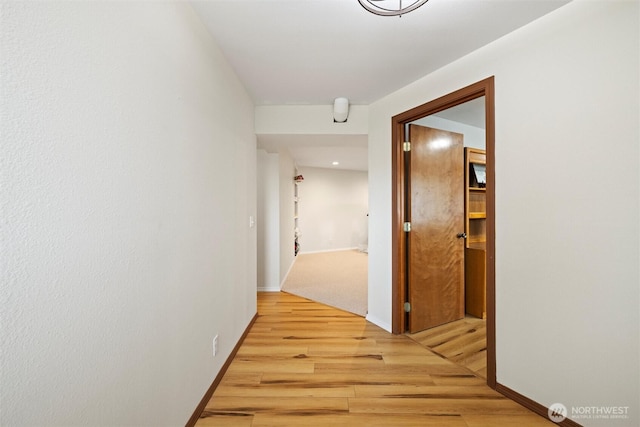 hall featuring light wood-style flooring and baseboards