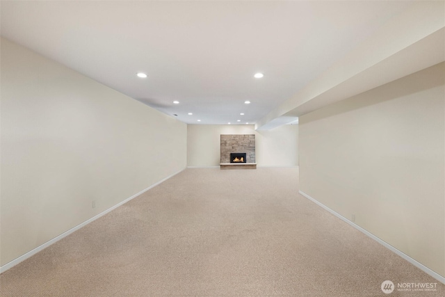 unfurnished living room with baseboards, a stone fireplace, carpet flooring, and recessed lighting