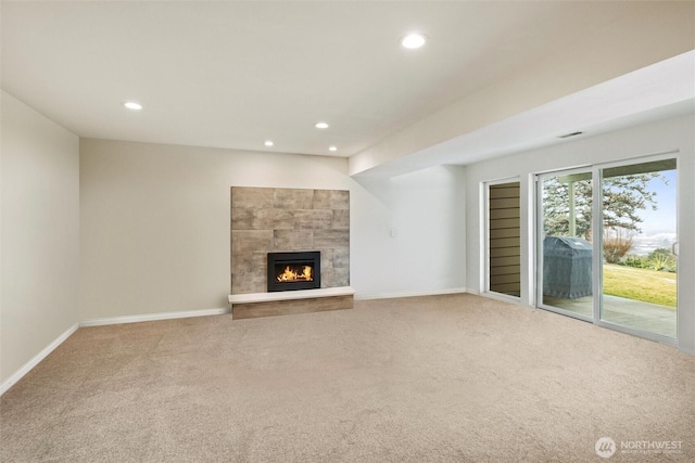 unfurnished living room with a tile fireplace, carpet flooring, baseboards, and recessed lighting