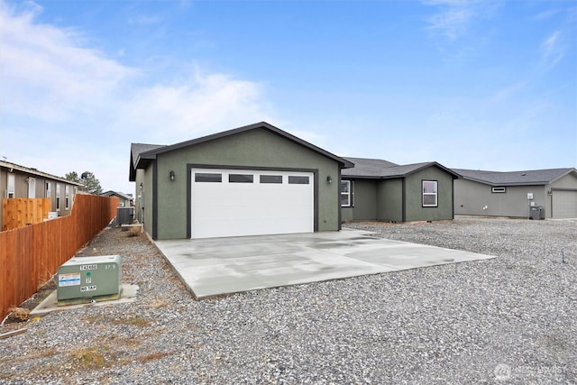 ranch-style home with a garage, central AC unit, concrete driveway, fence, and stucco siding