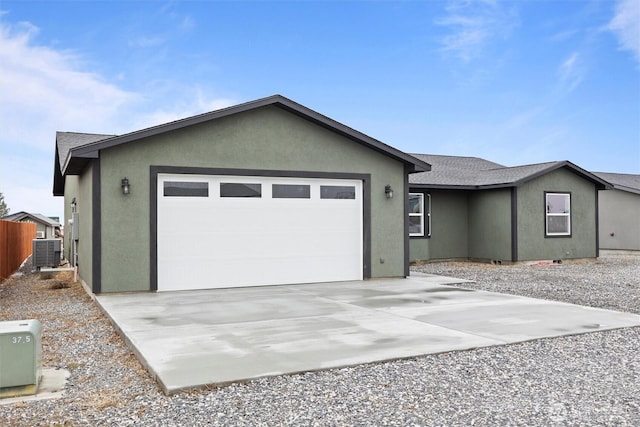 single story home with central AC unit, an attached garage, fence, driveway, and stucco siding