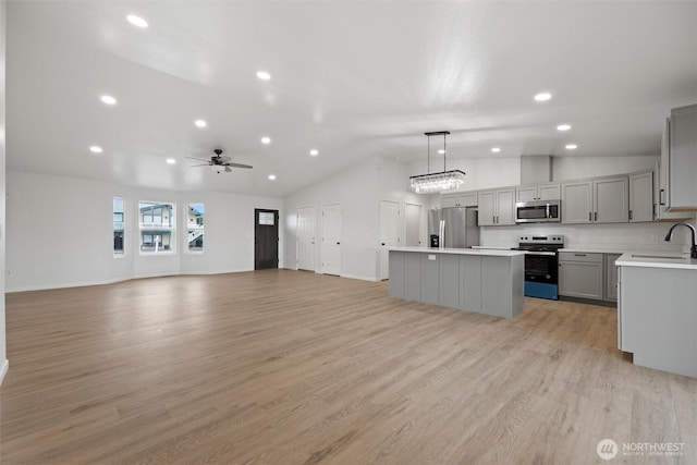 kitchen with a center island, decorative light fixtures, stainless steel appliances, light countertops, and gray cabinetry