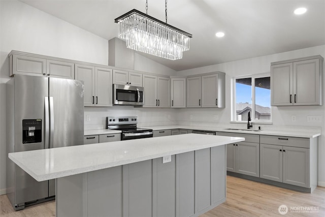 kitchen with appliances with stainless steel finishes, a center island, gray cabinetry, pendant lighting, and a sink