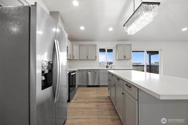 kitchen with a kitchen island, appliances with stainless steel finishes, light countertops, gray cabinetry, and a sink