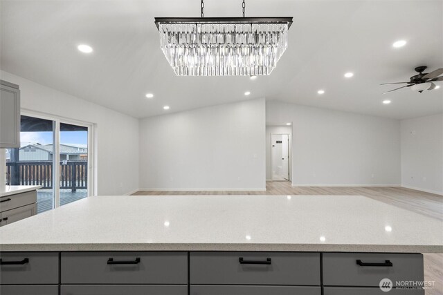 kitchen with gray cabinets, light wood-style flooring, a ceiling fan, open floor plan, and vaulted ceiling