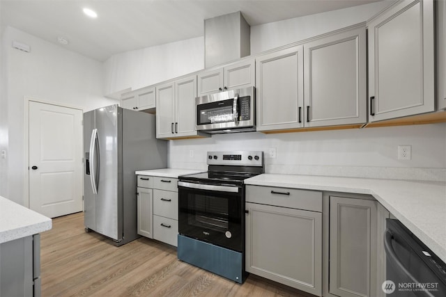 kitchen with recessed lighting, light countertops, light wood-style flooring, gray cabinetry, and appliances with stainless steel finishes