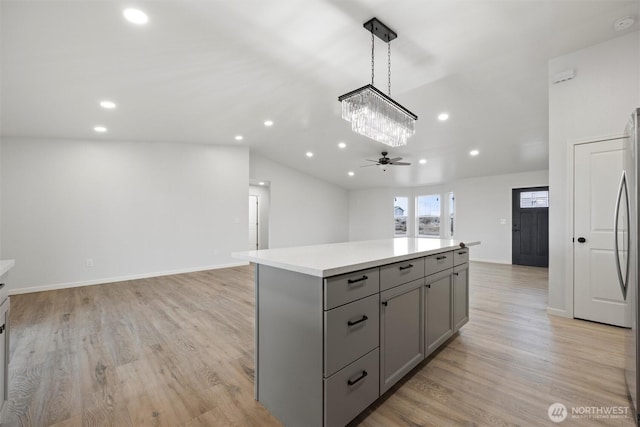 kitchen featuring a center island, decorative light fixtures, light countertops, gray cabinetry, and open floor plan