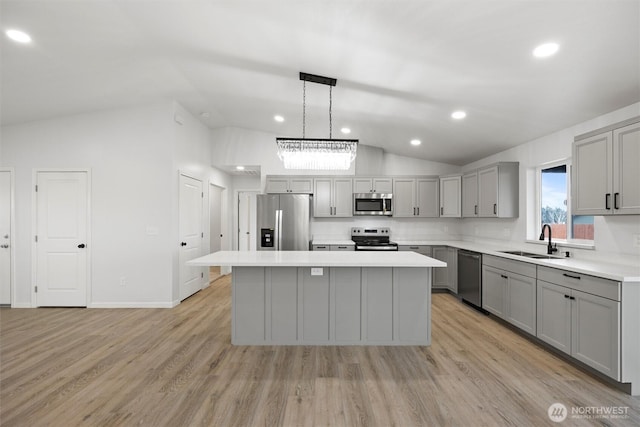 kitchen with a center island, pendant lighting, gray cabinets, light countertops, and appliances with stainless steel finishes