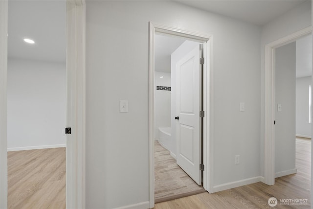 hall featuring light wood-type flooring and baseboards