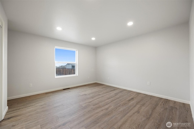 empty room featuring baseboards, light wood-type flooring, and recessed lighting