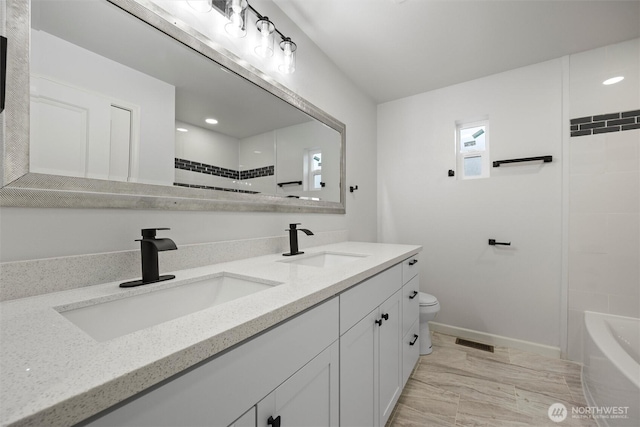 bathroom featuring toilet, double vanity, visible vents, and a sink