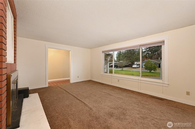 unfurnished living room featuring visible vents, a textured ceiling, carpet flooring, a fireplace, and baseboards