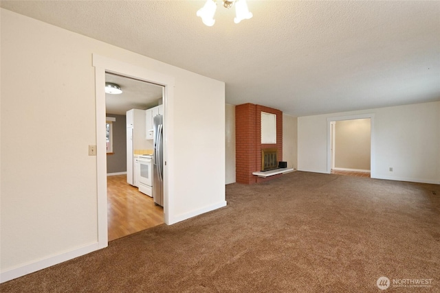 unfurnished living room featuring baseboards, a textured ceiling, a brick fireplace, and carpet flooring