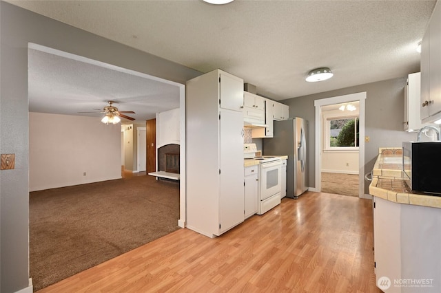 kitchen with electric range, a textured ceiling, white cabinetry, stainless steel fridge, and tile counters