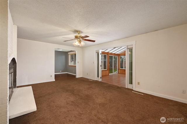 unfurnished living room with baseboards, carpet flooring, a fireplace, a textured ceiling, and a ceiling fan