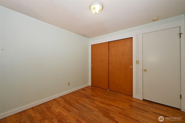 unfurnished bedroom with baseboards, a textured ceiling, and wood finished floors