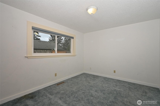 spare room featuring visible vents, baseboards, a textured ceiling, and dark carpet