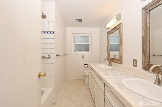 full bath with a sink, visible vents, toilet, and double vanity