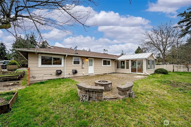 back of property featuring fence, an outdoor fire pit, a yard, a sunroom, and a patio area