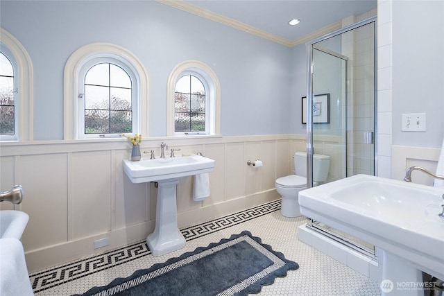 full bath featuring a wainscoted wall, a stall shower, toilet, and crown molding