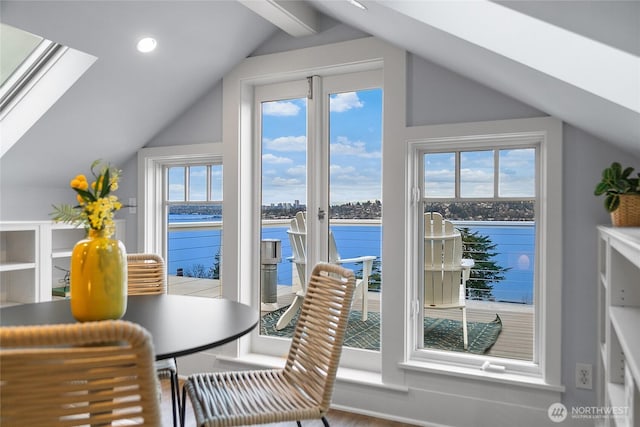 dining room with vaulted ceiling with skylight, a water view, and recessed lighting