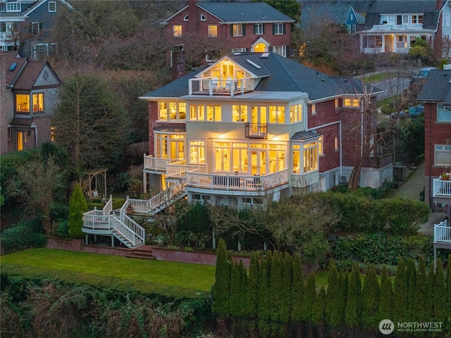 rear view of property featuring a lawn, stairway, and a balcony