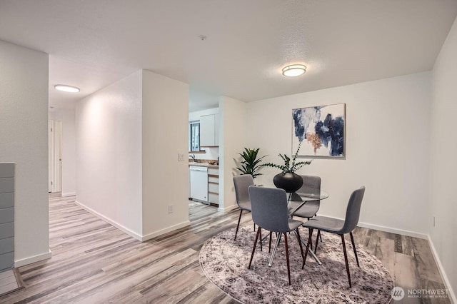 dining area with baseboards and light wood finished floors