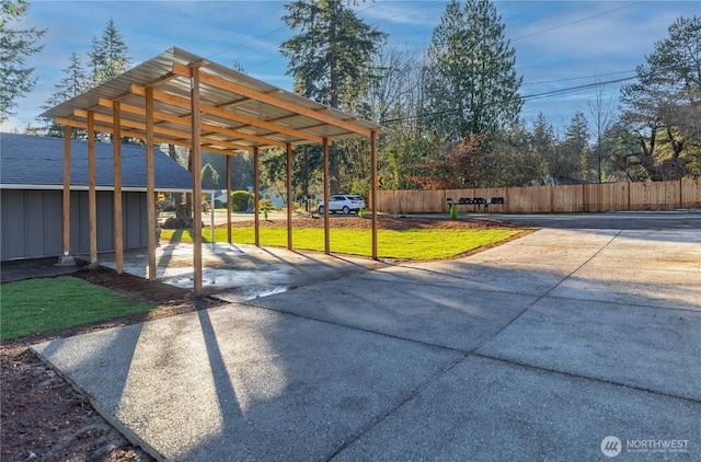 exterior space featuring a carport, concrete driveway, and fence