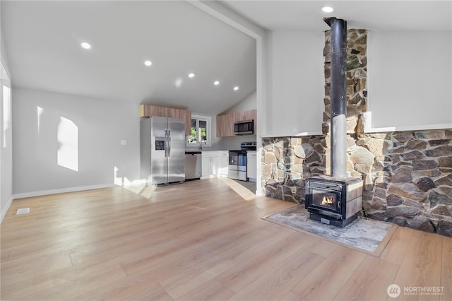 living room featuring high vaulted ceiling, baseboards, light wood-style floors, beam ceiling, and a wood stove