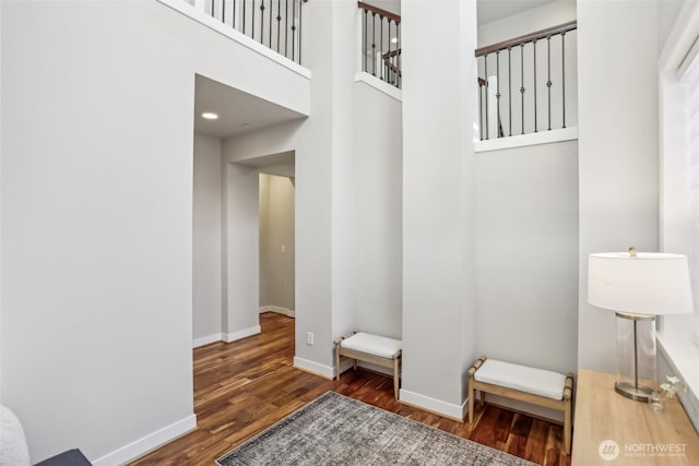 interior space with a towering ceiling, baseboards, and wood finished floors