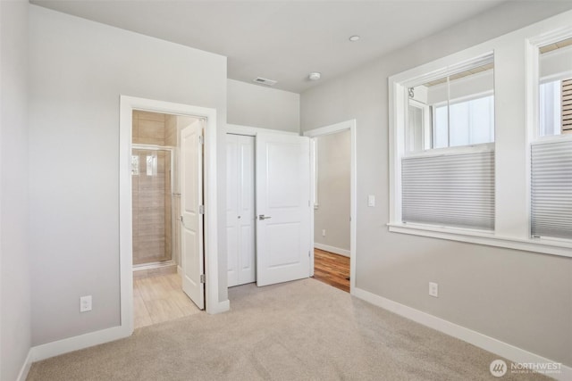 unfurnished bedroom featuring carpet, visible vents, ensuite bath, and baseboards