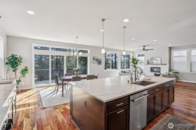 kitchen with stainless steel dishwasher, open floor plan, a sink, and wood finished floors