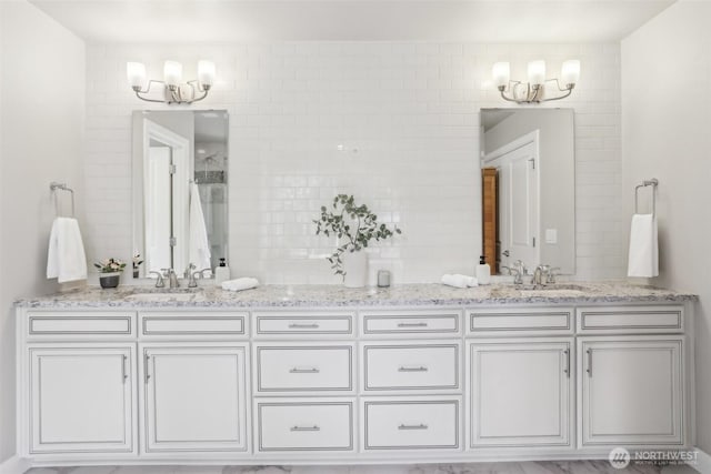 full bath featuring a notable chandelier, a sink, and double vanity