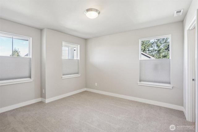 unfurnished room featuring light colored carpet, visible vents, and baseboards