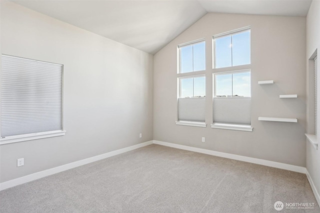 carpeted spare room featuring vaulted ceiling and baseboards