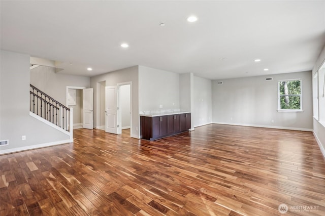 unfurnished living room with baseboards, stairway, wood finished floors, and recessed lighting