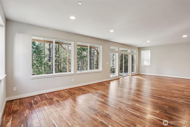 spare room featuring baseboards, wood finished floors, and recessed lighting