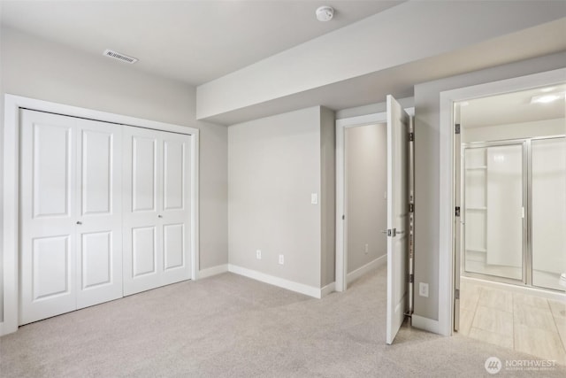 unfurnished bedroom with connected bathroom, light colored carpet, visible vents, baseboards, and a closet