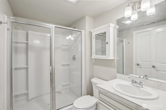 full bath featuring visible vents, vanity, a shower stall, and toilet