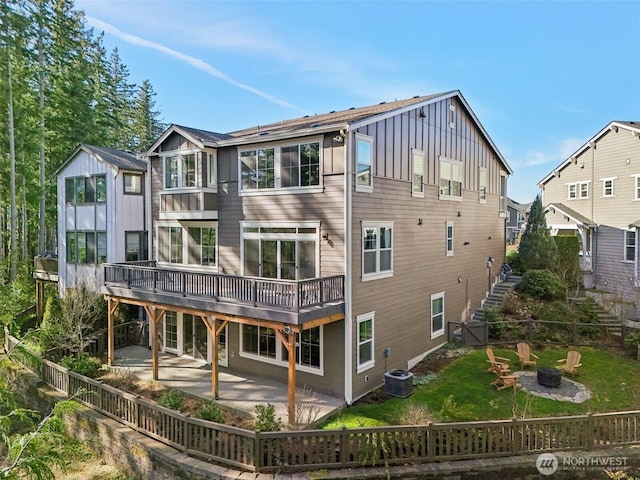 back of property with a lawn, central AC unit, an outdoor fire pit, a patio area, and a fenced backyard